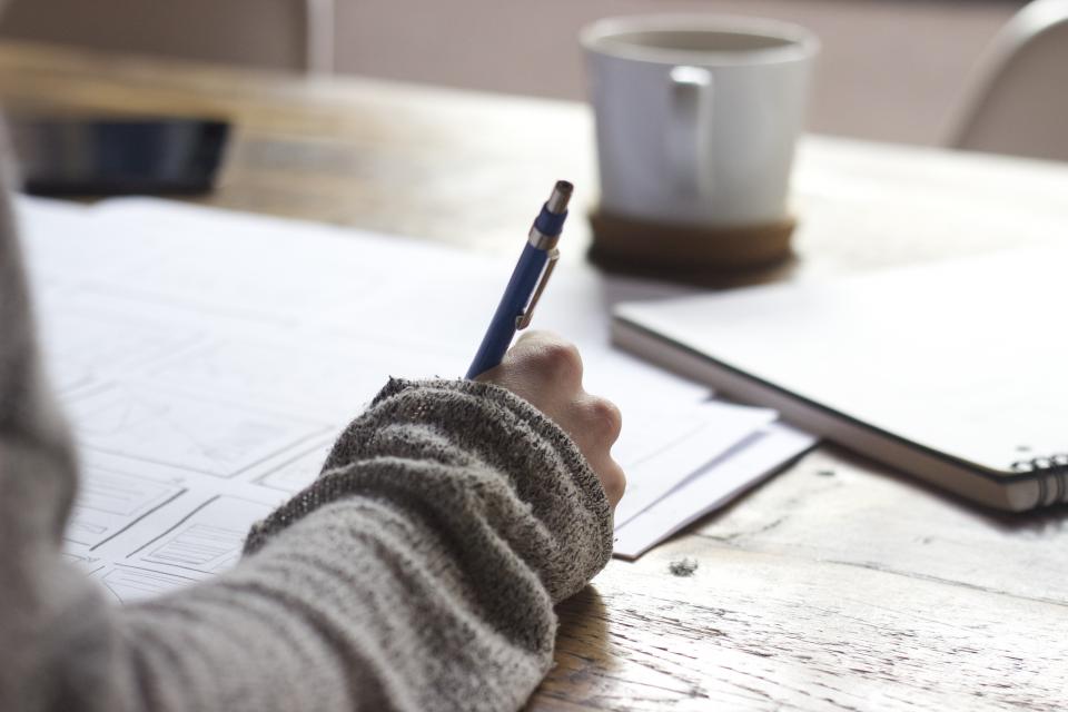 A notebook, pen, and coffee on a desk